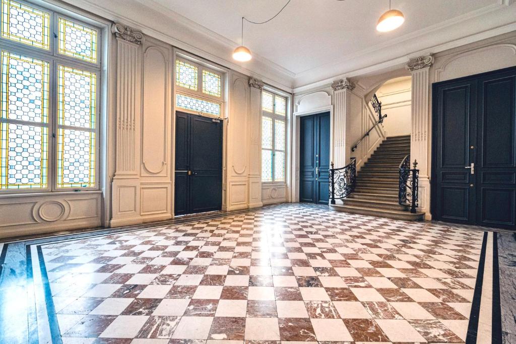 Red and white marble chequered entrance hall with ornate ironwork – 19th-century building, gîte in Reims historic centre