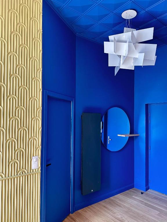 Entrance of La Rêverie Reims apartment – intense cobalt blue wall and gilded relief, characterful interior design